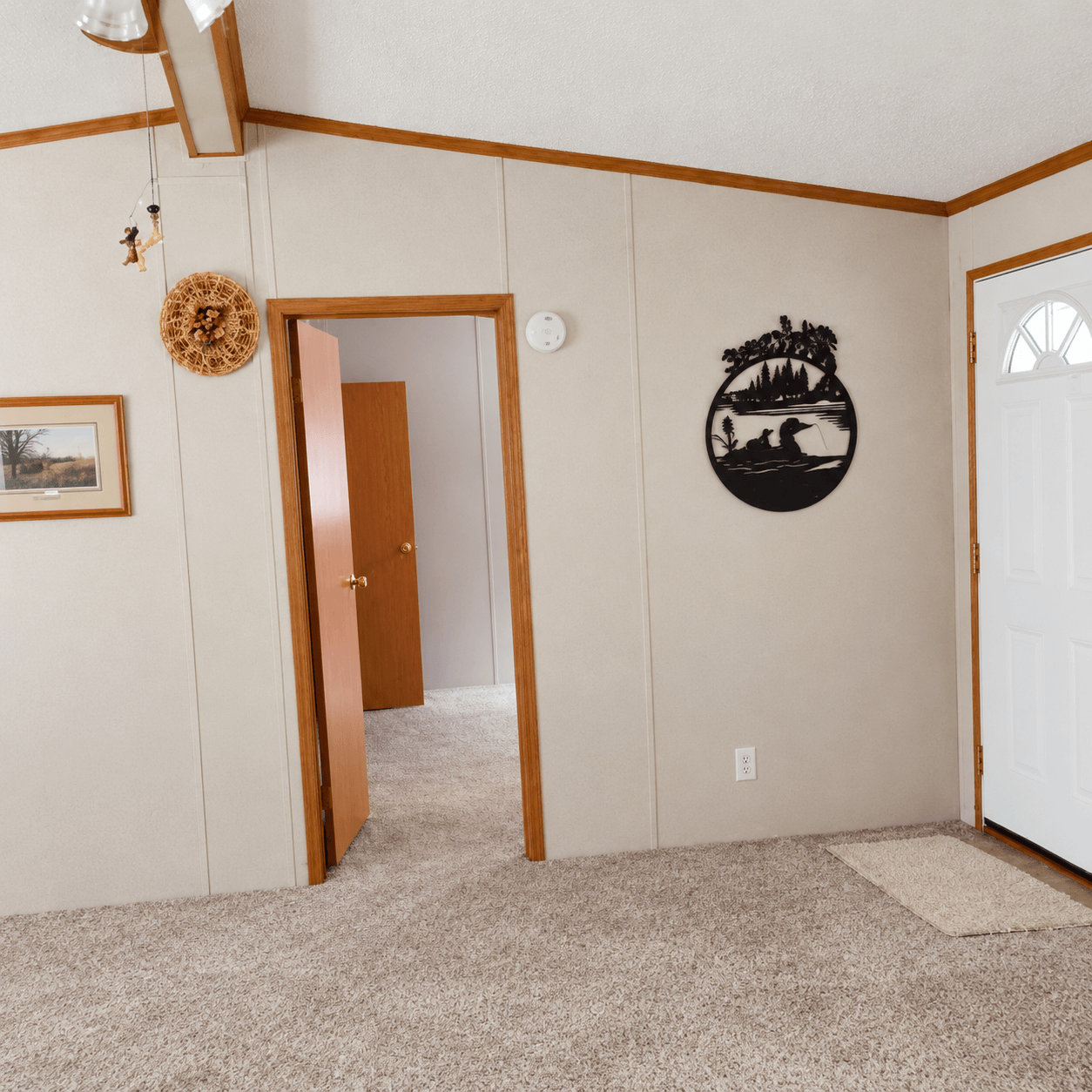 Empty room with wood trim, beige walls, carpet flooring, and decorative nature wall art