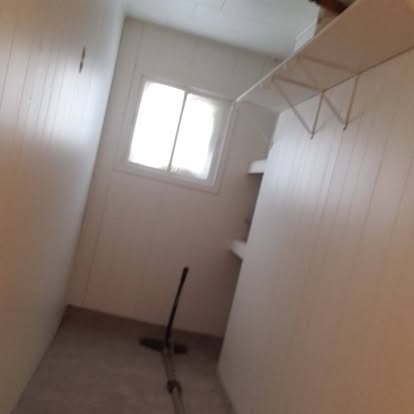 Empty room with white walls, window, clothes rack, and broom on floor