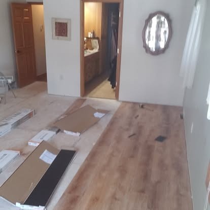 Flooring samples and installation materials displayed on subfloor in residential space