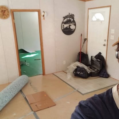 Interior room with cardboard flooring, rolled carpet, mirrors, and storage items during renovation