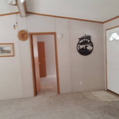 Empty room with wood-trimmed doorway, decorative wall clock, and framed artwork