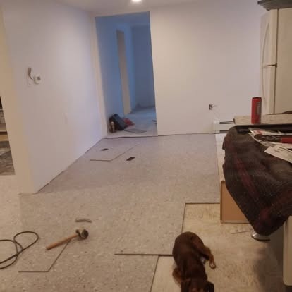 Unfinished basement room with drywall, flooring materials, and construction supplies scattered throughout