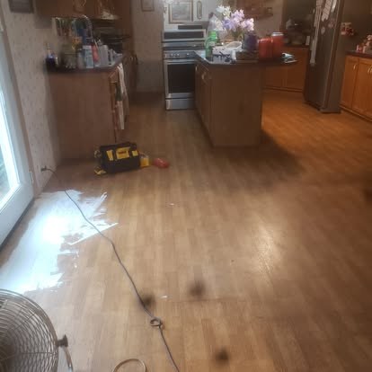Kitchen interior with wood flooring, cabinets, appliances, and work equipment on floor
