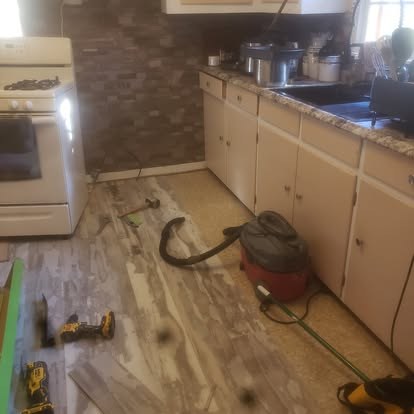 Kitchen flooring installation in progress with tools and equipment on subflooring