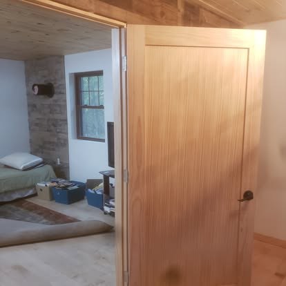 Interior renovation showing open doorway to bedroom with wood door frame and construction materials