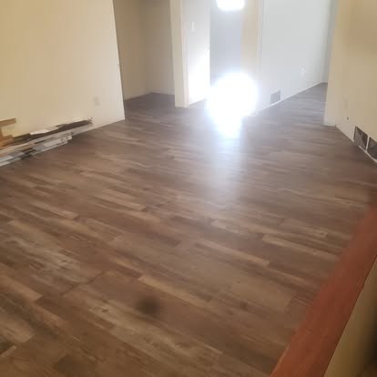 Empty room with laminate wood flooring and white walls lit by natural light
