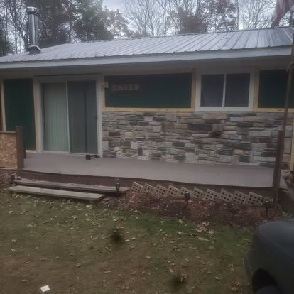 Modern single-story home with stone veneer siding, metal roof, and covered front porch
