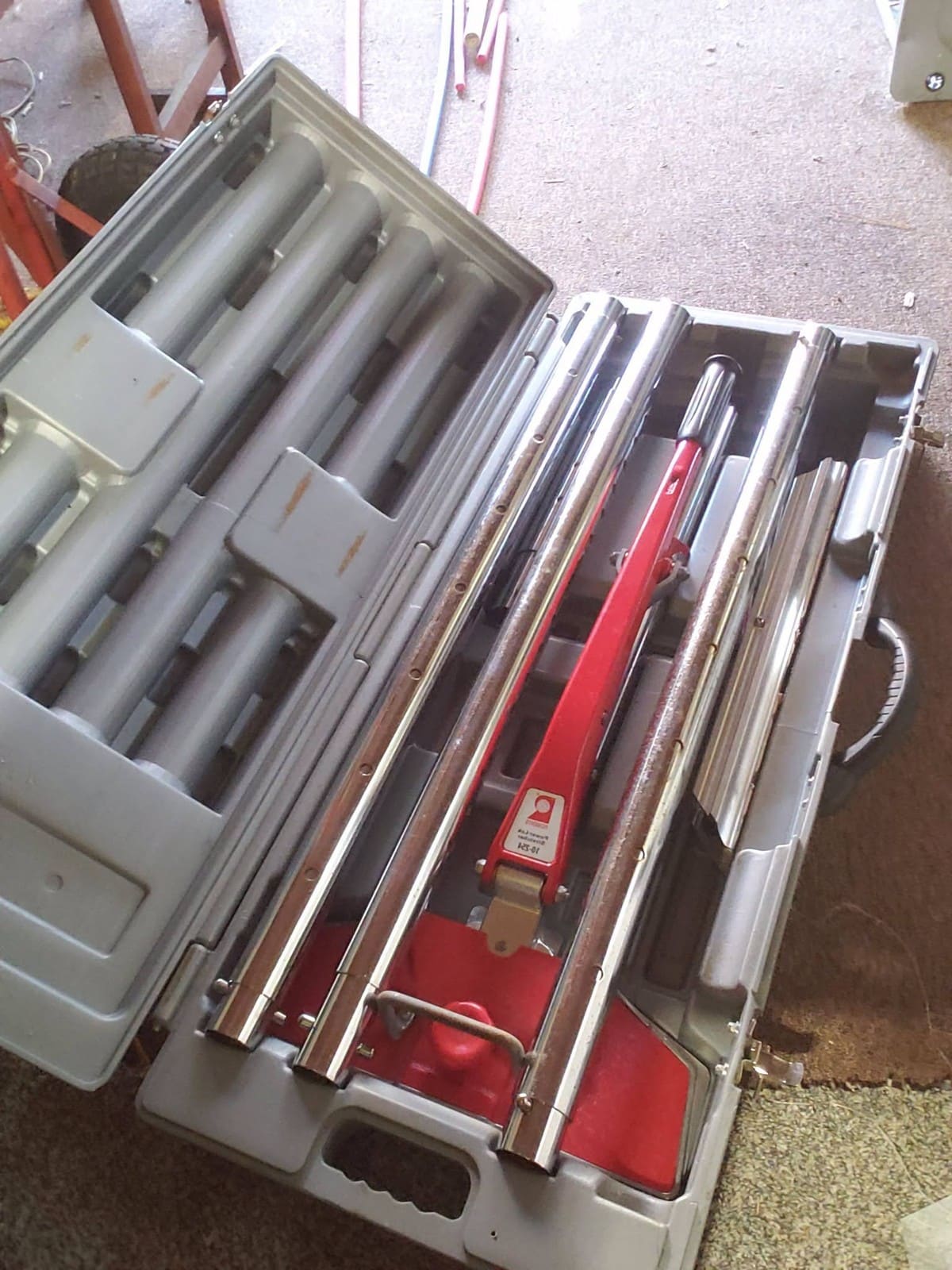 Open tackle box with fishing rods and red tackle storage trays