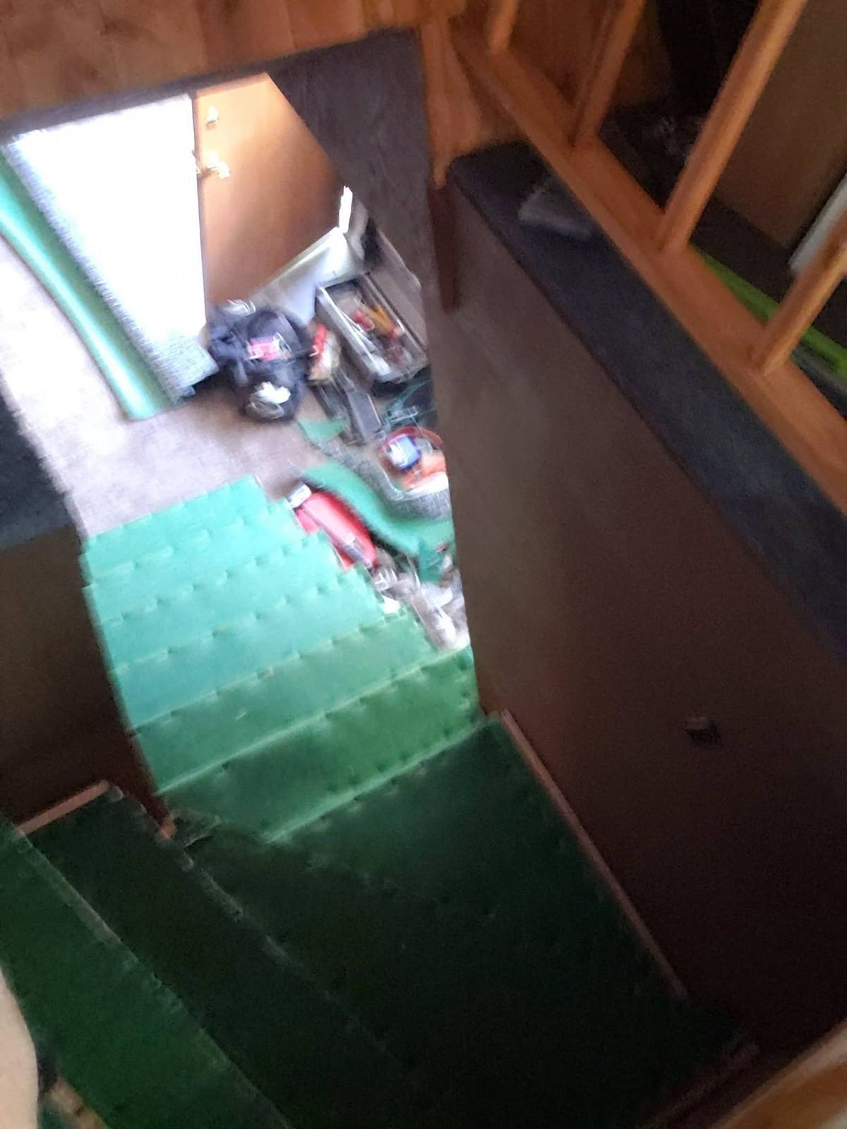 Overhead view of green storage containers with tools and red equipment on concrete floor